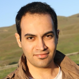 a photo of abdelrahman standing in front of a grassy landscape.