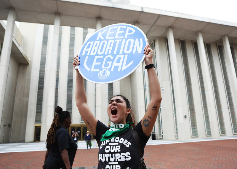 A protester shouting and holding up a 'keep abortion legal' sign.