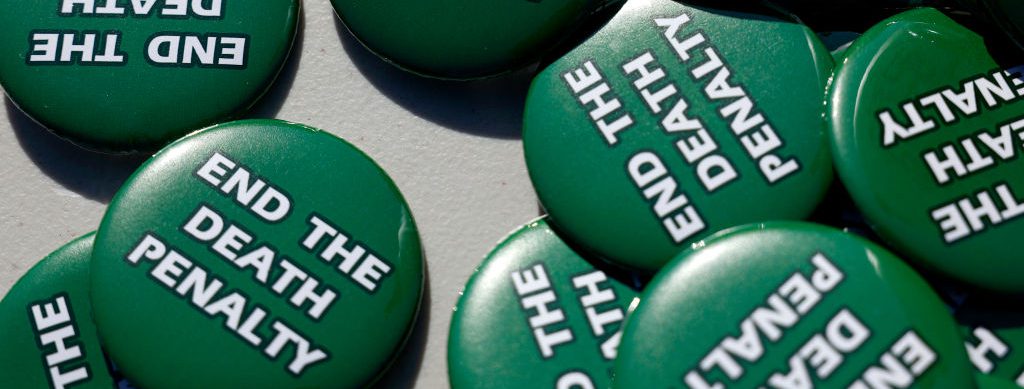 Pins with text opposing the death penalty sit on a table during a demonstration