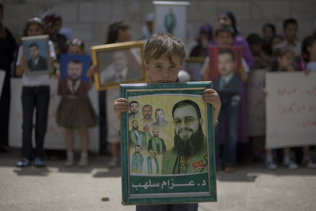 صبي فلسطيني يحمل صورة لقريب له مسجون وعضو في المجلس التشريعي الفلسطيني أثناء احتجاج في مدينة رام الله بالضفة الغربية في 5 يوليو / تموز 2009 يدعو إلى الإفراج عن الأسرى الفلسطينيين من السجون الإسرائيلية. © فادي عروري