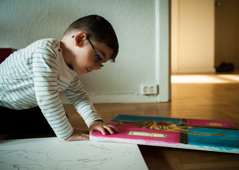 كهرمان، البالغ من العمر عامين، يطلع على رسومات والده. © منظمة العفو الدولية