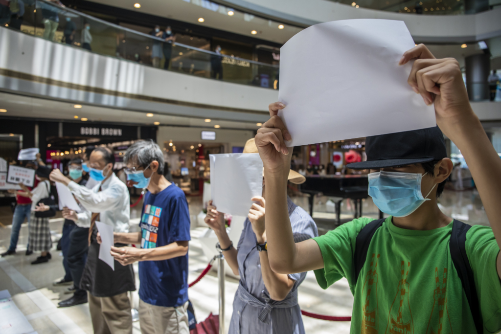متظاهرون يحملون لافتات بيضاء فارغة خلال تظاهرة في وقت الغداء في مركزٍ للتسوق في هونغ كونغ. (الصورة: Paul Yeung/Bloomberg via Getty Images)