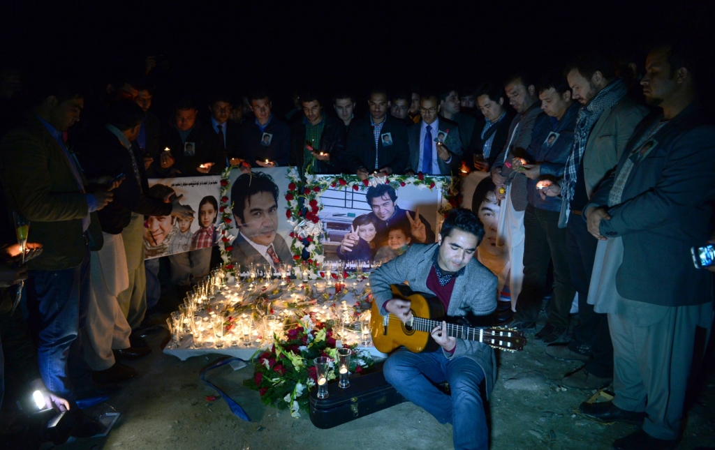 صديق مقرب من الصحفي سردار أحمد، الذي قُتل في 2014،  يعزف على الغيتار أثناء تأبين ذكراه بإيقاد الشموع (AFP/Getty)