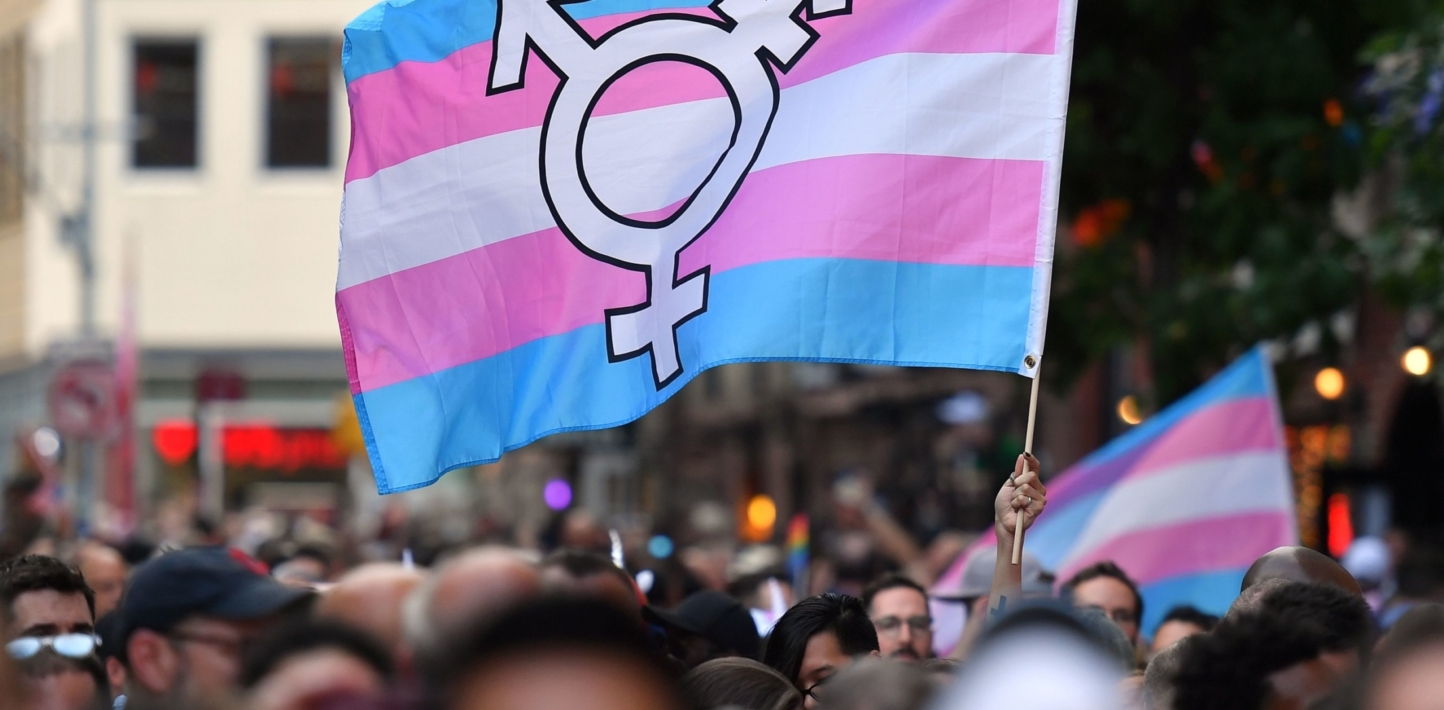 A person holds a transgender pride flag as people gather for a rally to mark the 50th anniversary of the Stonewall Riots.
