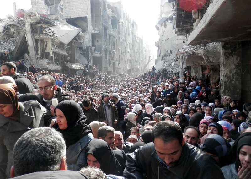 Residents wait to receive food aid distributed by UNRWA at the besieged Yarmouk camp, south of Damascus in January 2014. © unrwa.org