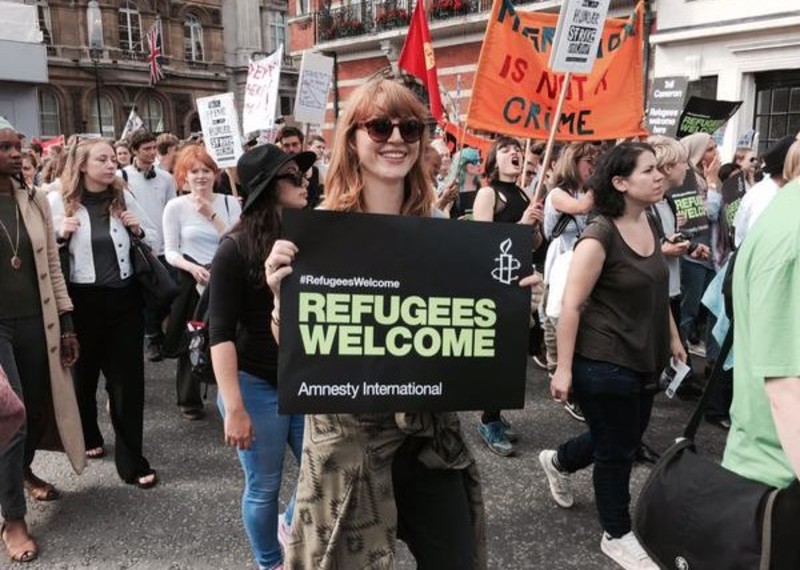 A woman demonstrates with a banner from Amnesty International Refugee Welcome campaign, London, United Kingdom, September 2015 © Amnesty International