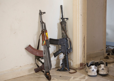 A Chinese made Kalashnikov and American M4 rifle (the latter captured from ISIS militants) lean against a wall in a building occupied by Syrian Kurdish YPG fighters in Al-Yarubiyah, Syria. © Matt Cetti-Roberts