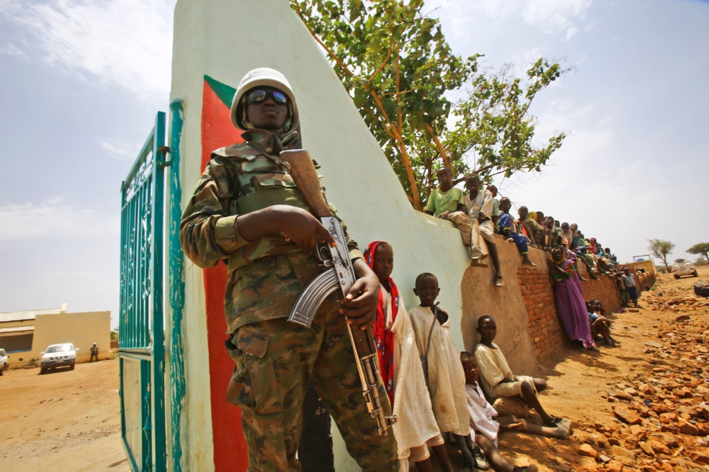 A UN peacekeeper stands guard as crowds of children and villagers gather to welcome Steven Koutsis (unseen), the United States' top envoy in Sudan, in the war-torn town of Golo in the thickly forested mountainous area of Jebel Marra in central Darfur on June 19, 2017. The town was a former rebel bastion which was recently captured by Sudanese government forces. © ASHRAF SHAZLY/AFP/Getty Images