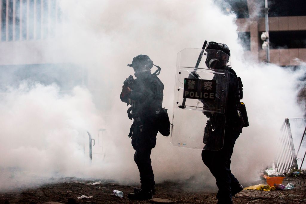 Police officers stand surrounded by tear gas during a rally by protesters against a controversial extradition law proposal outside the government headquarters in Hong Kong on June 12, 2019. - Violent clashes broke out in Hong Kong on June 12 as police tried to stop protesters storming the city's parliament, while tens of thousands of people blocked key arteries in a show of strength against government plans to allow extraditions to China. (Photo by ISAAC LAWRENCE / AFP) (Photo credit should read ISAAC LAWRENCE/AFP/Getty Images)