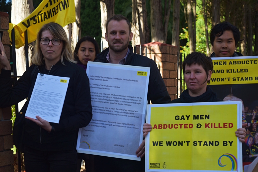 Activists from Amnesty Australia ringing the doorbell of the Russian Consulate in Sydney, where they handed in thousands of signatures