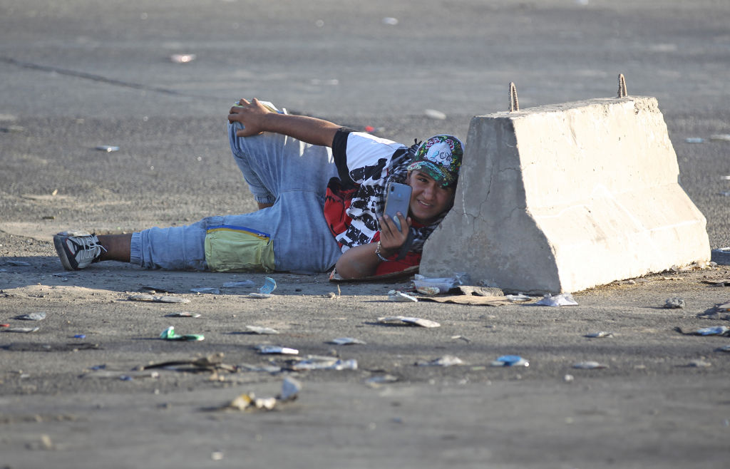 An Iraqi protester takes cover during a demonstration against state corruption, failing public services, and unemployment in the Iraqi capital Baghdad's central Khellani Square on October 4, 2019