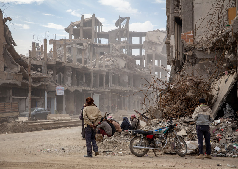 Men wait by the side of the road for casual labour in Raqqa, Syria, on 5 February 2018. Many labourers end up clearing partially destroyed or damaged buildings, a very risky endeavour; in many of them, the Islamic State armed group placed mines, which frequently kill and injured civilians. © Amnesty International