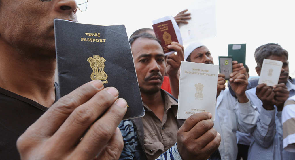 Foreign workers show their passports as they gather outside a Saudi immigration office waiting for an exit permit. The kingdom is the only Gulf state that continues to require all migrant workers to obtain an exit permit in order to leave the country.