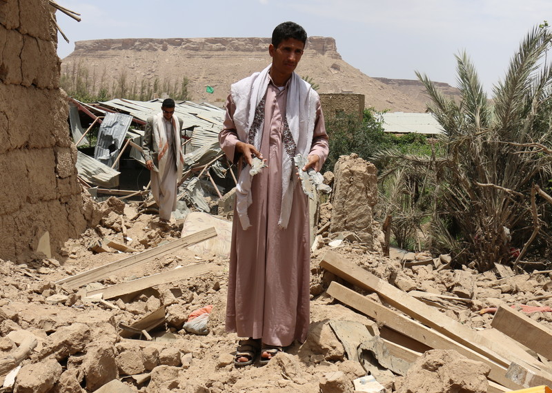 A member of the al-Sailami family stands in rubble of destroyed house in al-Safra, Sa'da