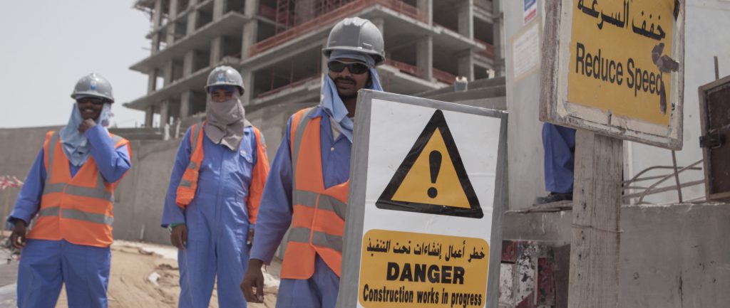 Migrant construction workers pose for a picture outside of their work site at The Pearl, a man-made chain of islands off the coast of northern Doha.© Sam Tarling