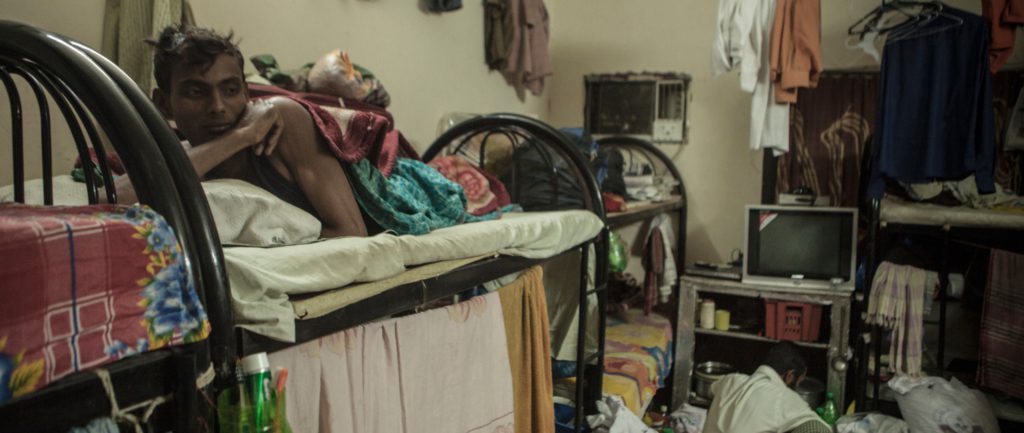 After a day of work, migrant workers rest in a labor camp dormitory in Doha's Industrial Area. © Sam Tarling