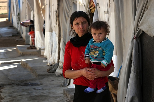 A displaced Iraqi woman from the Yazidi community, who fled violence between Islamic State (IS) group jihadists and Peshmerga fighters in the northern town of Sinjar, stands at a camp for internally displaced persons (IDP) in the Sharia area, some 15 kilometres from the city of Dohuk, on November 17, 2016.