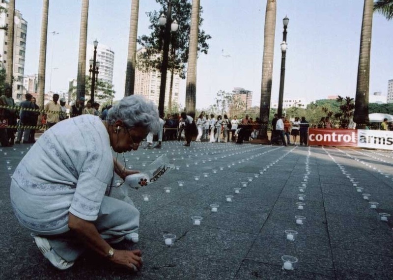 A woman lays a candle on a road in São Paulo, Brazil, as part of an arms control awareness initiative. Credit: Amnesty International.
