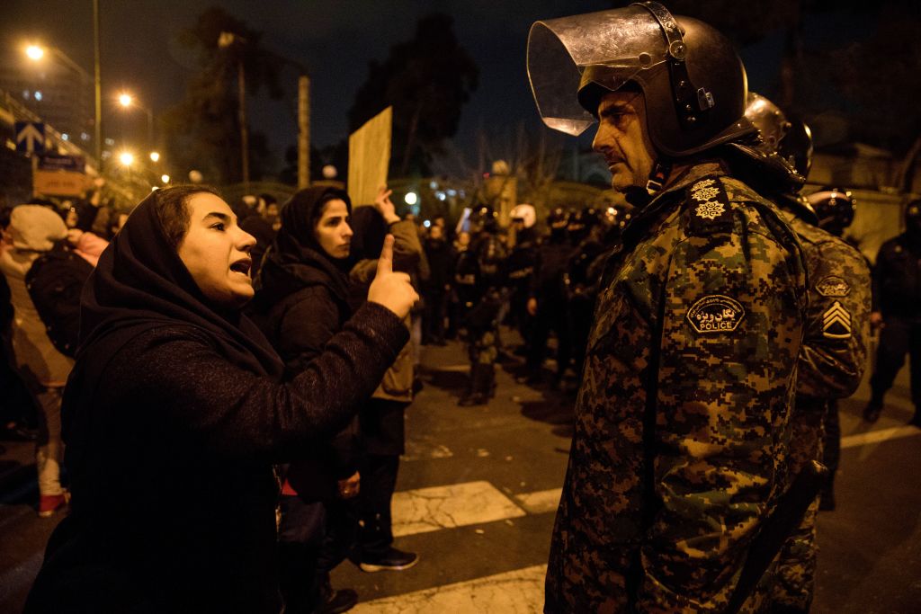 A woman attending a candlelight vigil, in memory of the victims of Ukraine International Airlines Boeing 737, talks to a policeman following the gathering in front of the Amirkabir University in the Iranian capital Tehran on January 11, 2020.
