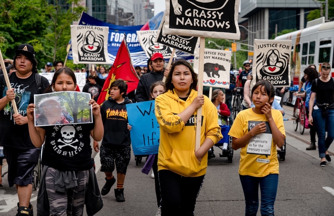 In June 2019, over 40 members of the Grassy Narrows community travelled 1,700km from their home to demand that the government make good on its promise to build a care centre for survivors of mercury poisoning. Since 2012, the youth of Grassy Narrows have held an annual rally for mercury justice. Today their cries for justice have been taken up by people across Canada and beyond.