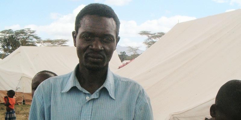A man standing outside tents in a internally displaced persons' camp