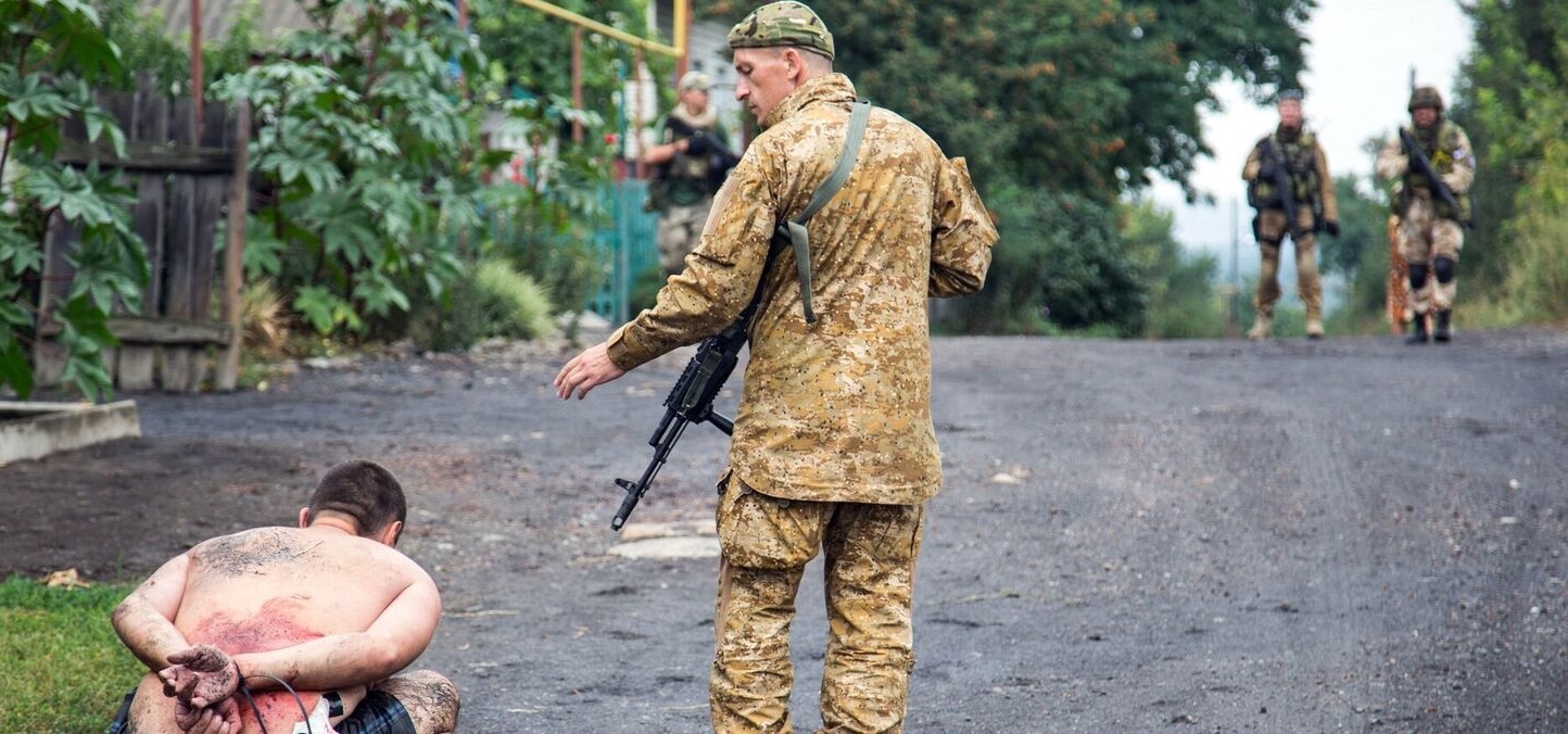 Armed Ukrainian forces detain a pro-Russian militant in the village of Chornukhine in the Lugansk region on August 18, 2014. A Ukrainian warplane was blown out of the sky over rebel-held territory as fierce clashes between government troops and pro-Russian insurgents left dozens of civilians dead. At least 415,800 people have fled their homes due to fighting between government forces and pro-Russian separatists in eastern Ukraine, the UN refugee agency said on August 20. AFP PHOTO/ OLEKSANDR RATUSHNIAK (Photo credit should read OLEKSANDR RATUSHNIAK/AFP/Getty Images)