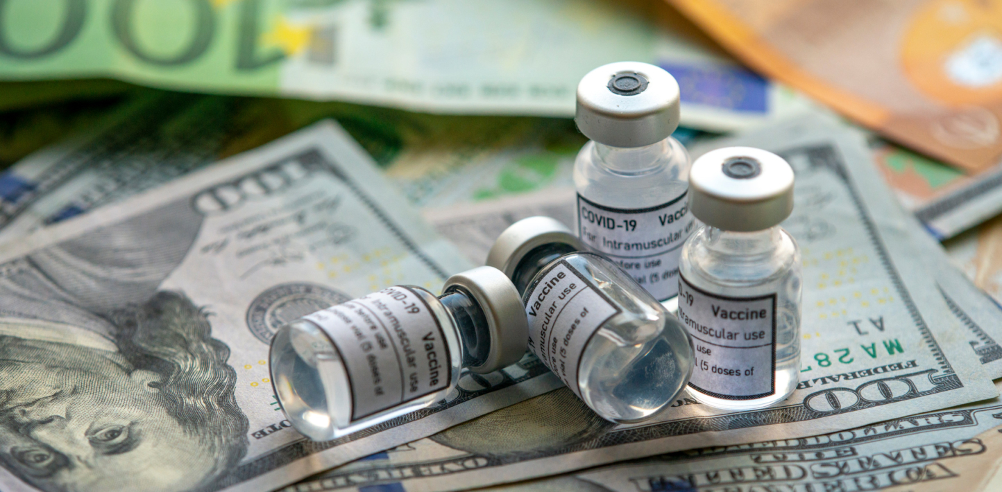 Covid-19 vaccine on a stack of US dollar and euro banknotes bills