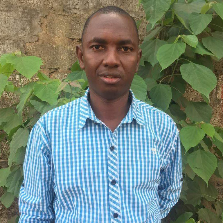 a portrait of Souleyman Sow. He is wearing a blue checked shirt 