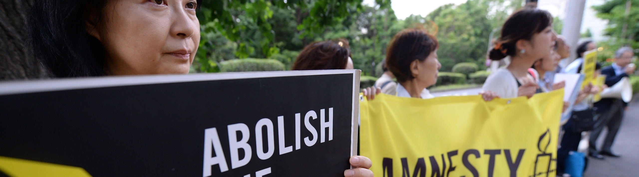 protesters march, holding signs that read Abolish the Death Penalty