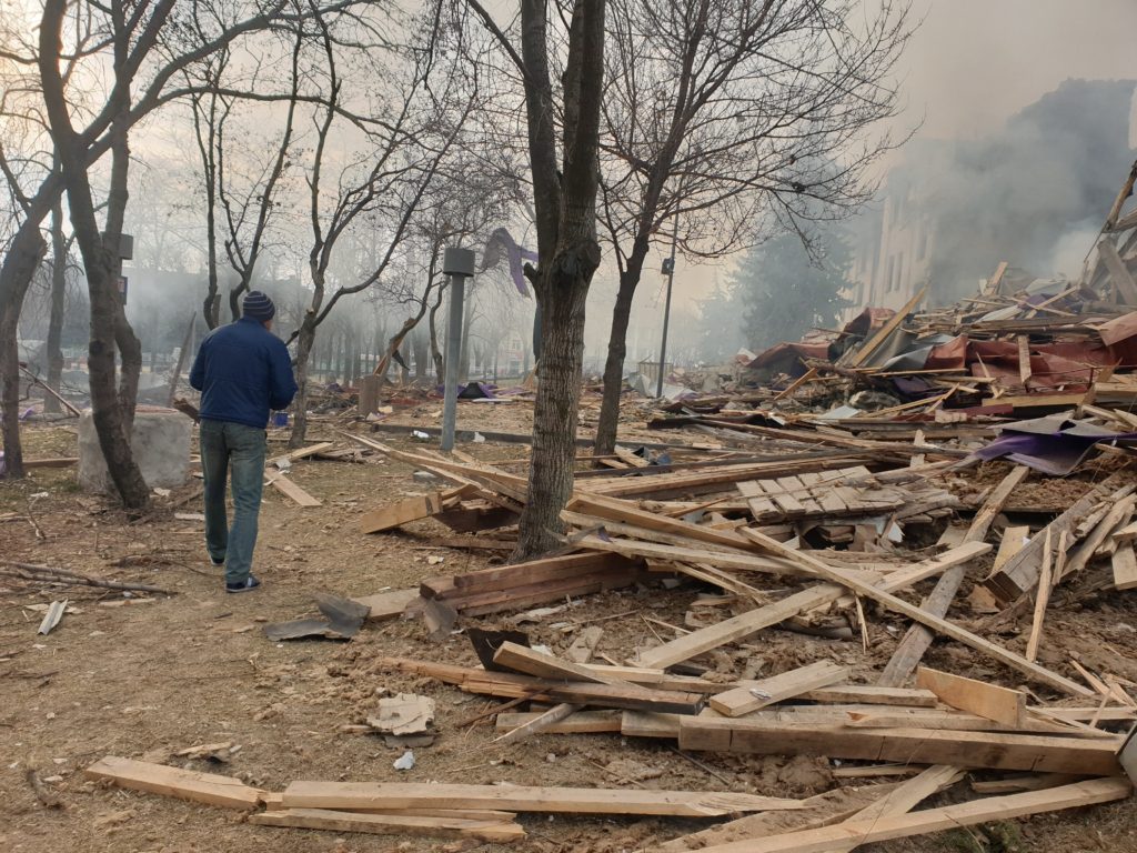 	A man walks by a debris field to the side of the theatre shortly after the attack.