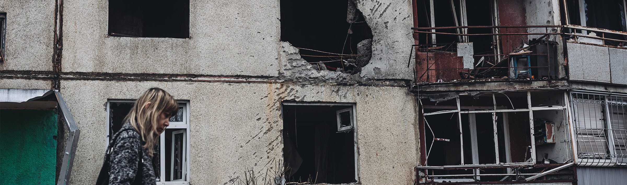 A woman walks past a house damaged by Russian shelling in Kharkov, Ukraine on 2 April, 2022.