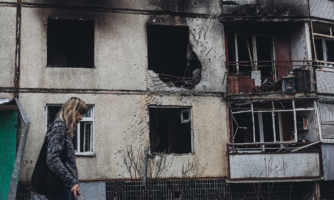 A woman walks past a house damaged by Russian shelling in Kharkov, Ukraine on 2 April, 2022.