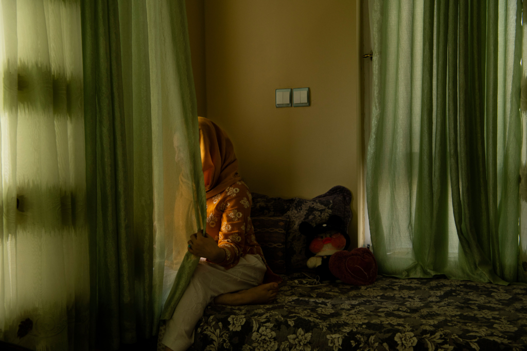 An Afghan woman poses for a portrait in her home.
