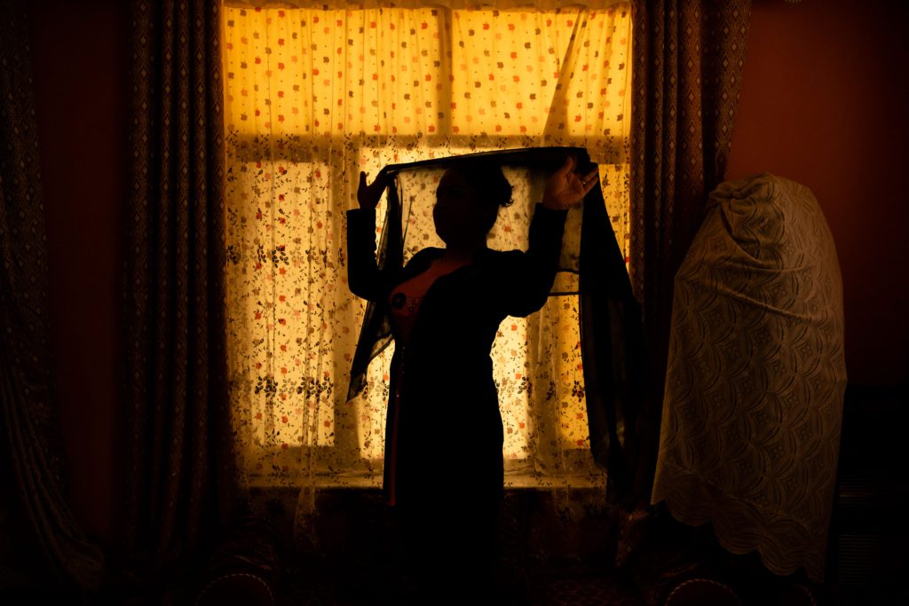 An Afghan woman poses for a portrait in her home.