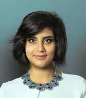 a portrait of loujain. Her hair is side sweapt and reaches just below her ears. She is wearing a necklace with blue gems and a pale green shirt. 