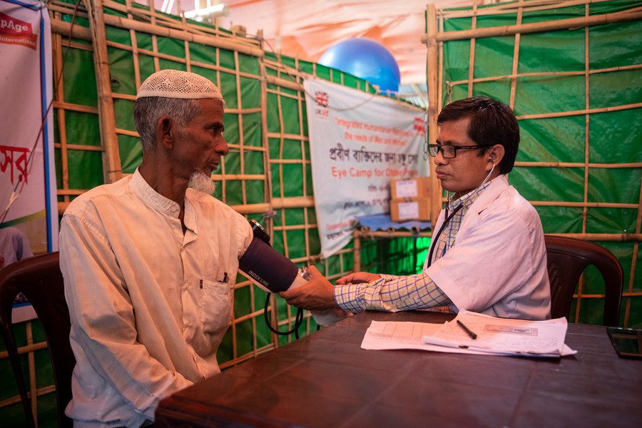 an older Rohingya man gets his blood pressure checked by a doctor at a refugee camp in Bangladesh. 