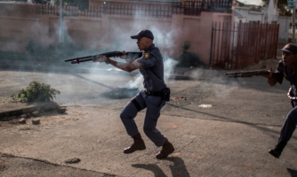 Police officers fire rubber bullet as they chase protestors in the streets of Johannesburg