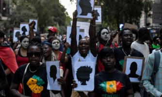 A crowd of protesters holds pictures of silhouettes.