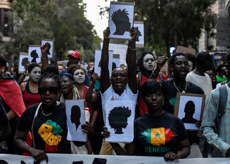 A crowd of protesters holds pictures of silhouettes. 