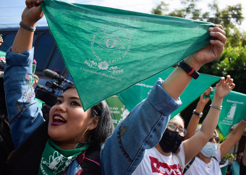 Young people hold up green triangular bandanas . 