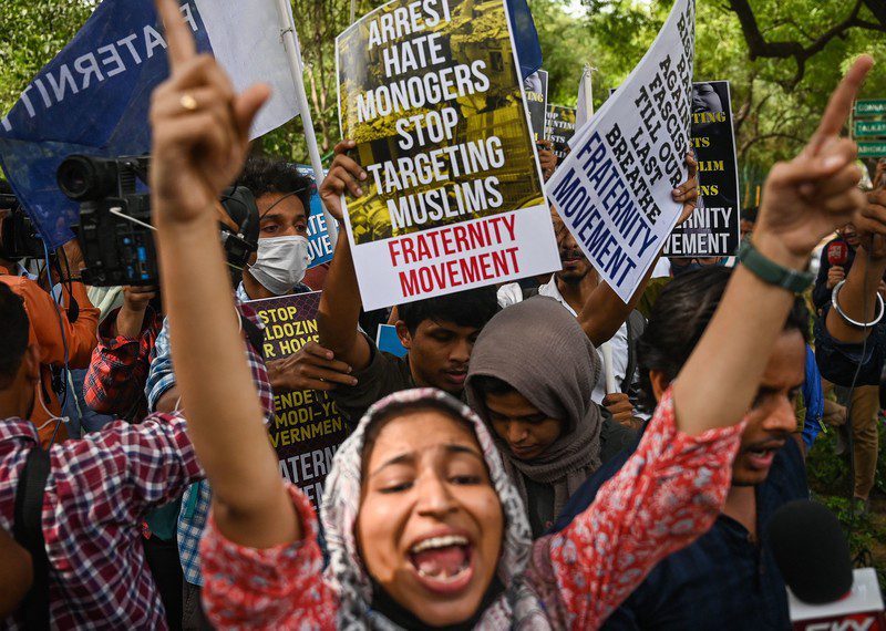 A woman holds up her hands and shouts in the midst of a crowd of other protesters and placards.