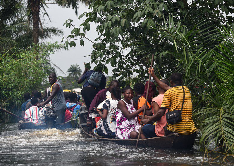 People are crowded onto small boats navigating floods.