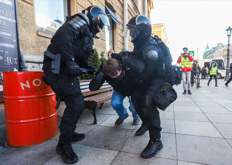 Two heavily armored police officers force down a protester.