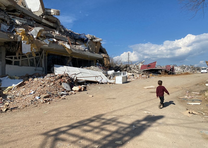 Boy walking by a building destroyed by the earthquakes in Gaziantep (Nurdagi), Türkiye March 2023