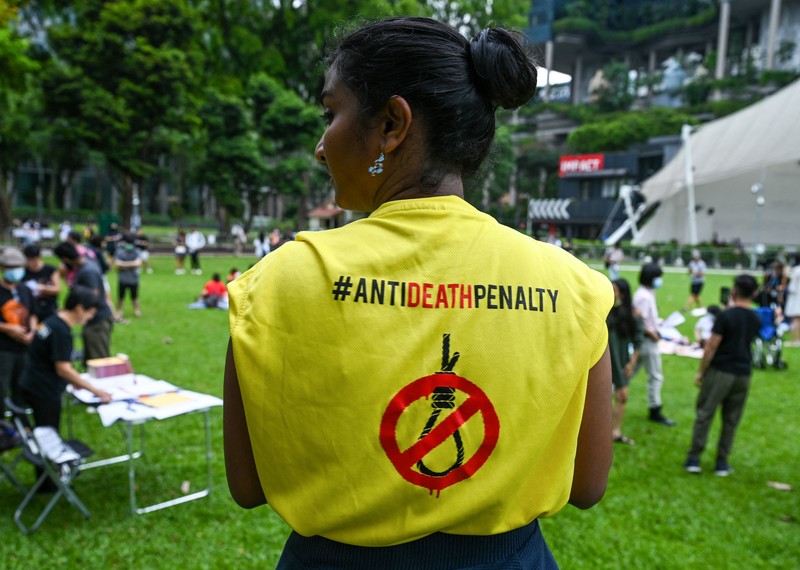 Back of a person wearing a t-shirt with the hashtag #AntiDeathPenalty and an image of a noose with a stop sign over it. 