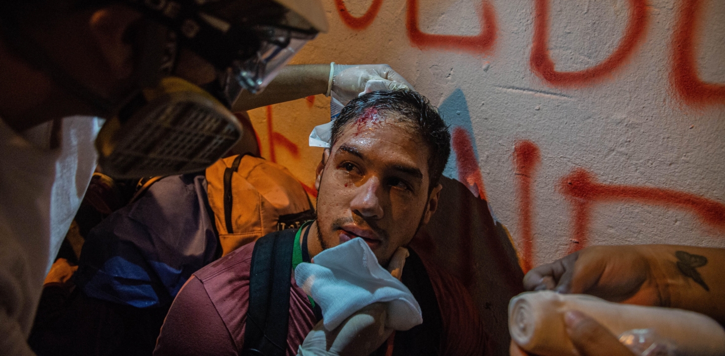 A medic tends to journalist Luis Becerra who is bleeding from a cut on the forehead.