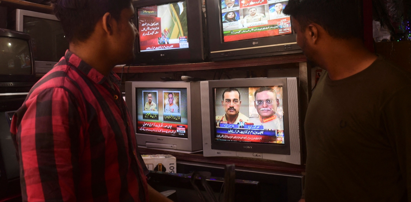 People watch a news television broadcast of the nomination of the next Pakistan's army Chief General Syed Asim Munir, at a market in Karachi