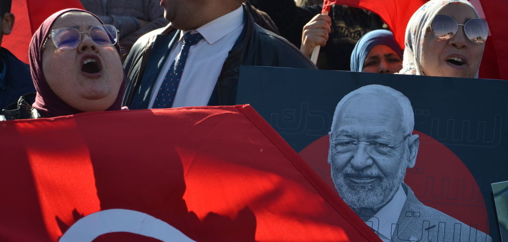 People holding signs and Tunisian flags to show support for Ennahdha Movement leader Rached Ghannouchi who is about to be questioned about a number of complaints submitted by security personnel, according to what was confirmed by leaders in the Ennahda Movement in front of the Anti-Terrorism Judicial Pole at Charguia on 21 February 2023