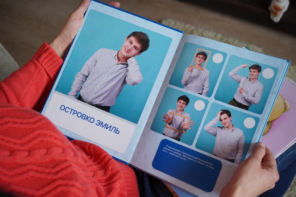 A woman is looking down at a book with photos of her son Emil. In the photos he is smiling and striking poses.