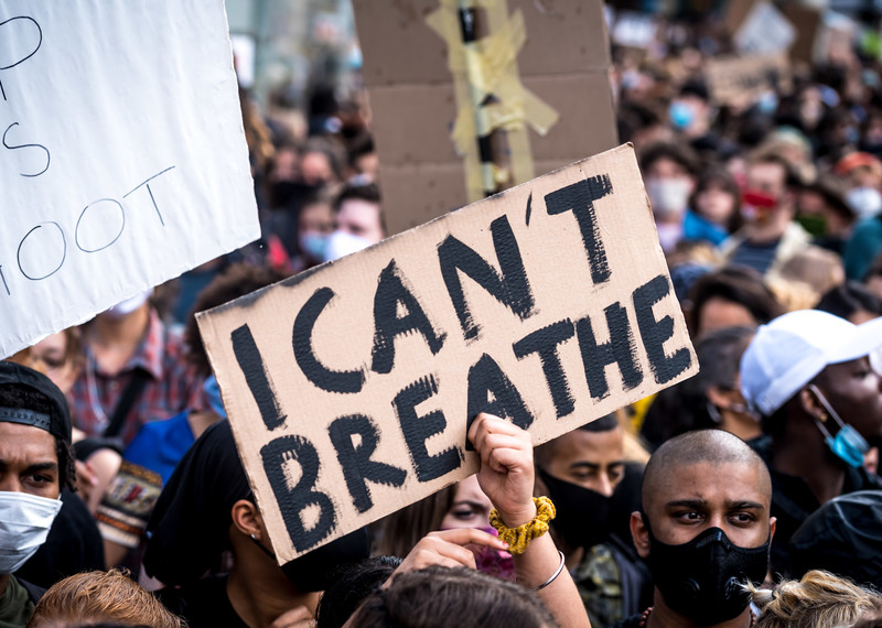 A crowd of protesters and a placard which says 'I can't breathe'. 